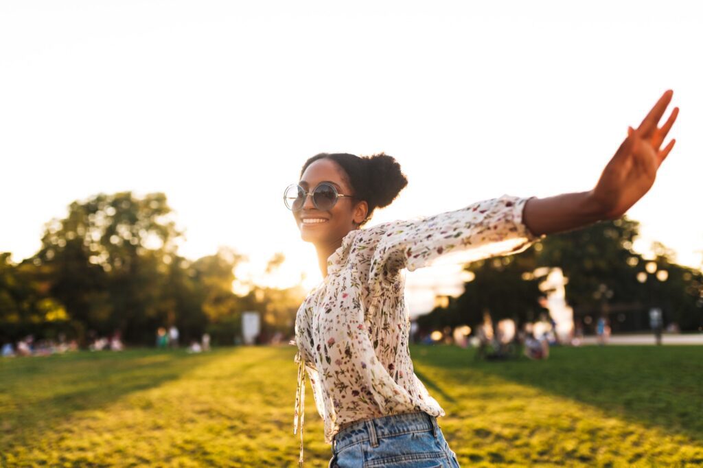 Beautiful smiling african girl in sunglasses joyfully spending time in city park